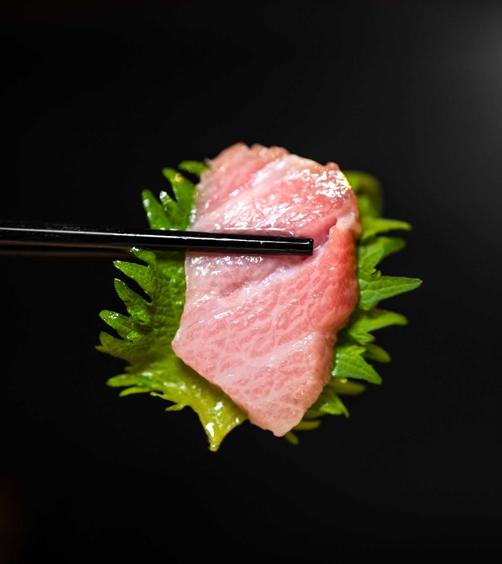 Beautiful cut of sashimi being held by chopsticks