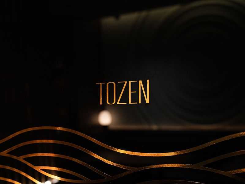 Tozen Sushi Bar Logo on dark mirrored glass